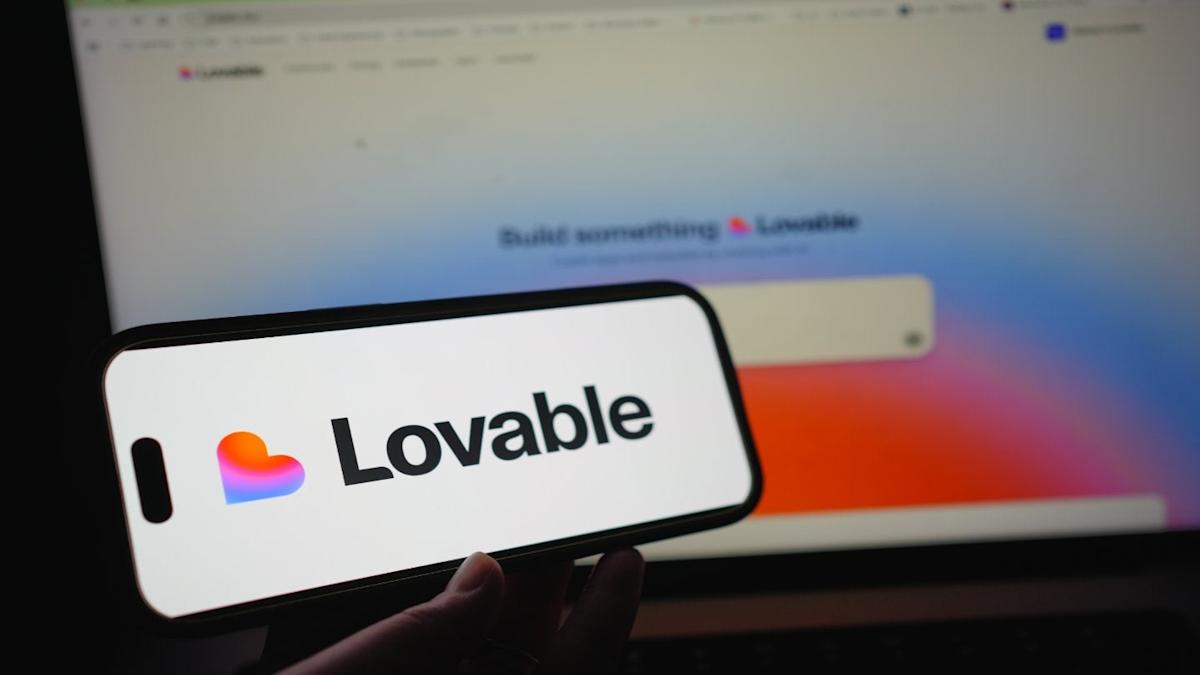 Lovable logo on a mobile screen wtih the Lovable's landing page open on a computer on the background.